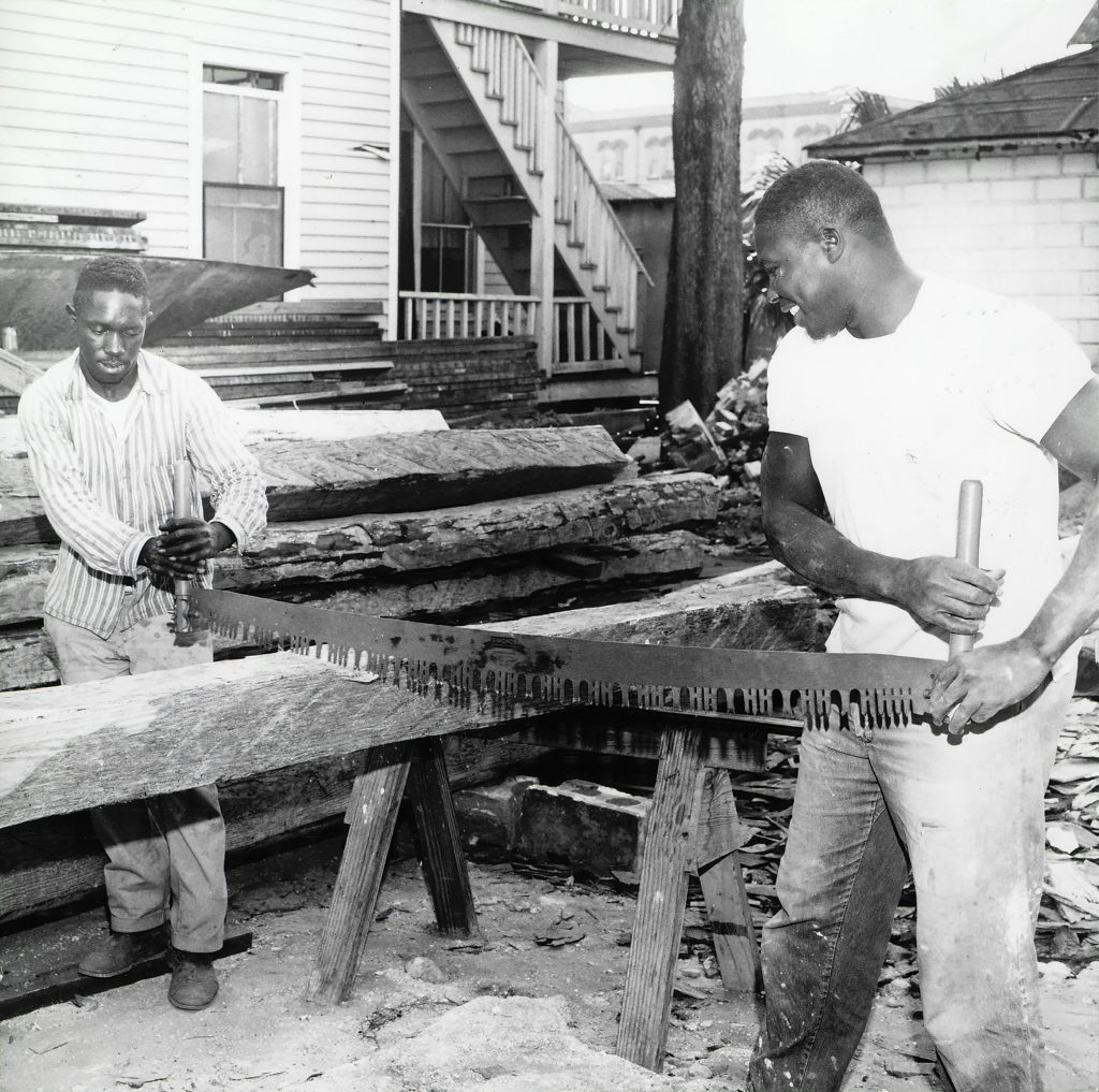 Two individuals operating a two-person saw during the construction of the Old Blacksmith Shop on the Judson Property